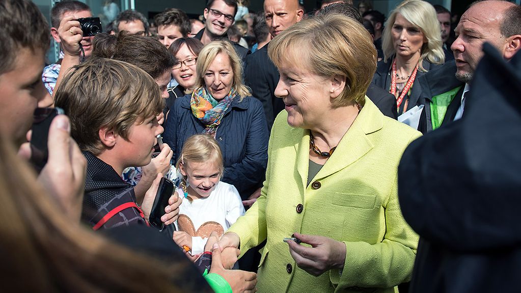 Kanzlerin Merkel umringt von Besuchern.