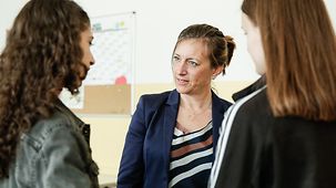Die stellvertretende Regierungssprecherin Ulrike Demmer beim Besuch der Hugo-Gaudig-Schule anlässlich des EU-Projekttages im Gespräch mit zwei Schülerinnen.