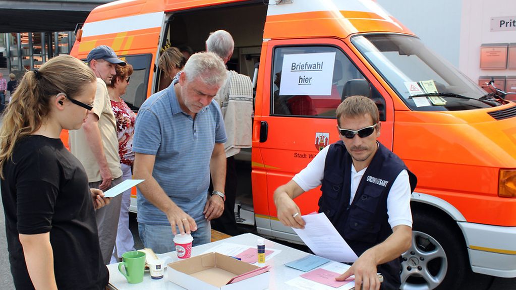 Drei Menschen vor dem mobilen Bürgerbüro der Stadtverwaltung Wittstock/Dosse.