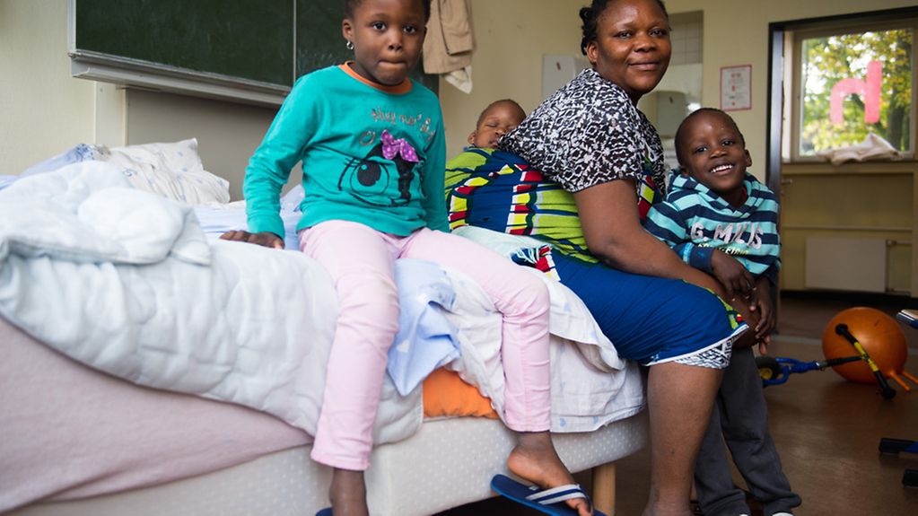 La Nigériane Evbuomwan Zoreth est assise avec ses enfants sur un lit dans un centre d'accueil de migrants à Düsseldorf