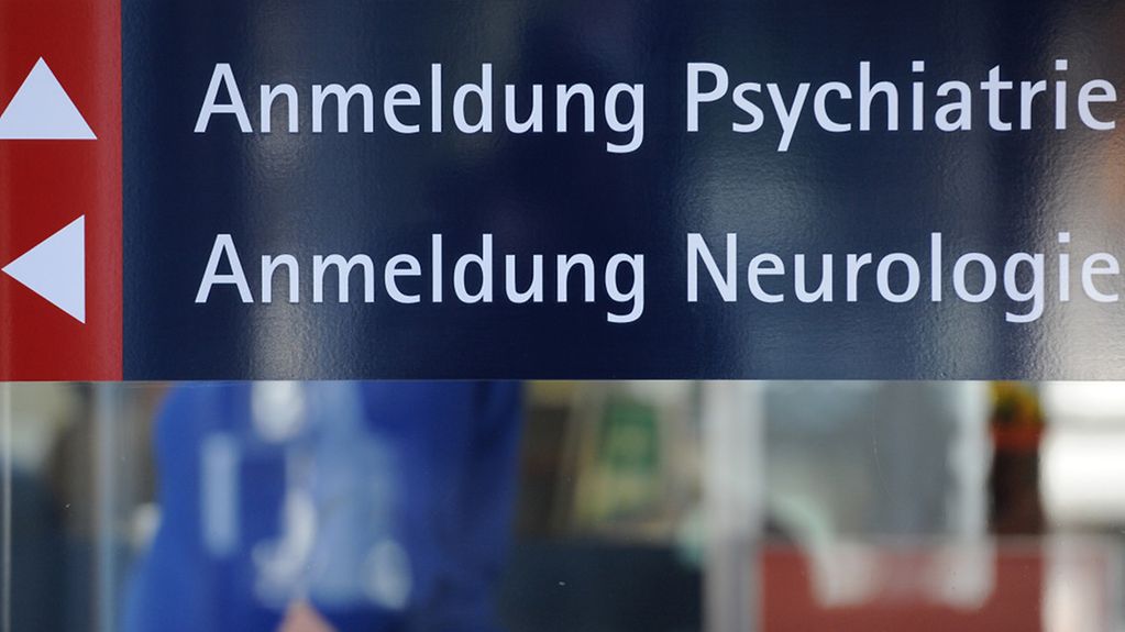 Ein Schild mit der Aufschrift 'Anmeldung Psychiatrie' und 'Anmeldung Neurologie' ist an einem Gebäude im Bezirksklinikum in Regensburg.