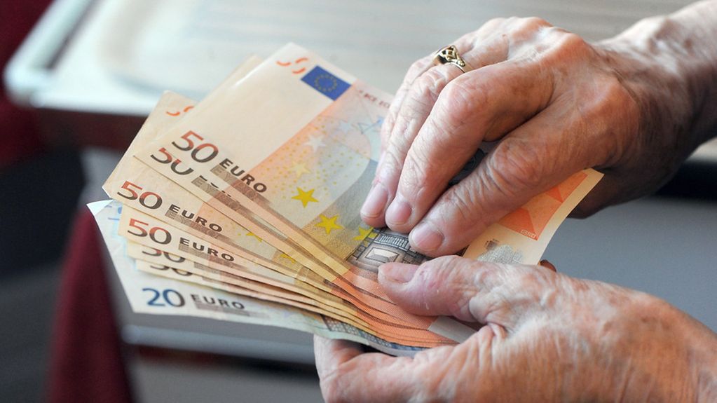 Die Hände einer alten Frau halten Geldscheine.