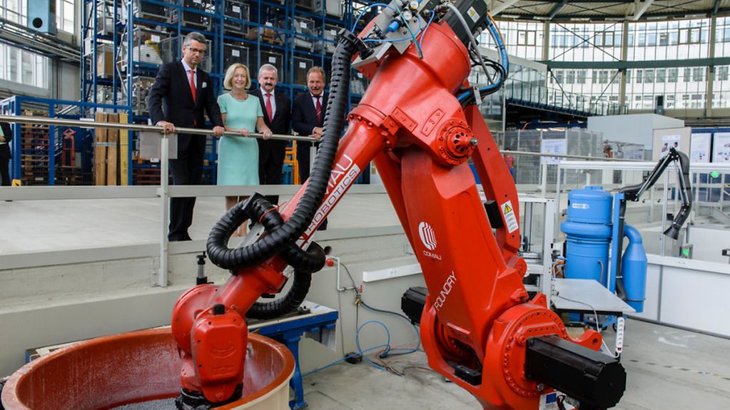 Bundesforschungsministerin Wanka betrachtet Roboter.
