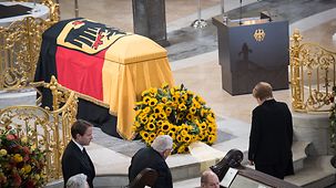 Chancellor Angela Merkel stands, head bowed, in front of Helmut Schmidt's coffin in Hamburg's St. Michael's Church.