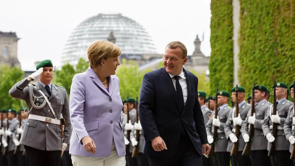 Chancellor Angela Merkel walks beside the Danish Prime Minister Lars Løkke Rasmussen.