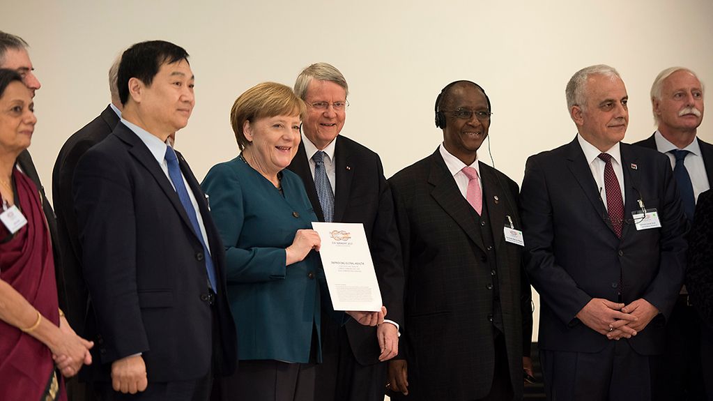 Chancellor Angela Merkel with a communiqué from the G20 academies of sciences