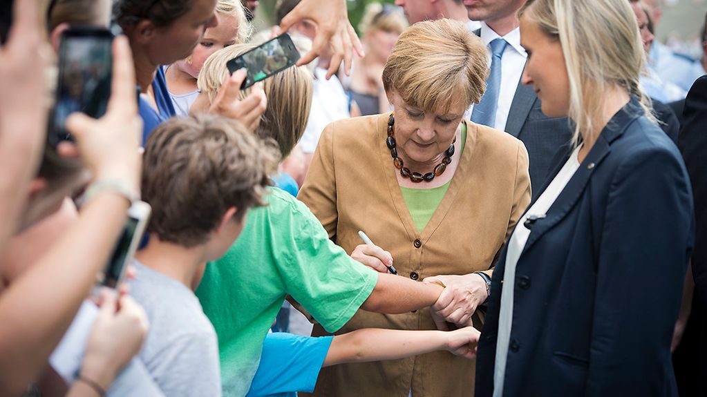 Bundeskanzlerin Angela Merkel schreibt beim Kanzlerin-Rundgang zum Tag der offenen Tür Autogramme.