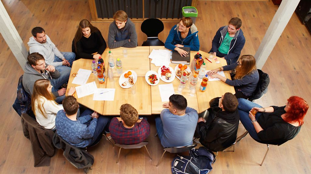 Eine Projektgruppe mit Jugendlichen sitzt an einem großen Tisch.