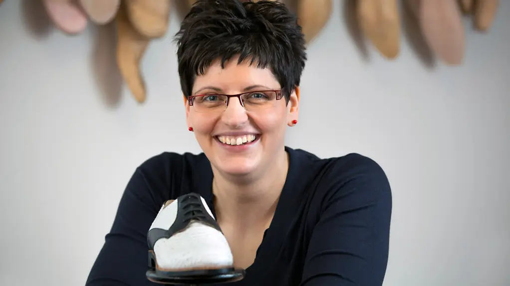 Juniorchefin Ulrike Schröder-Schubert steht hinter einem ihrer maßgefertigten Schuhe.