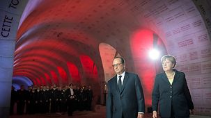 Bundeskanzlerin Angela Merkel und Frankreichs Präsident François Hollande gehen im Beinhaus von Douaumont.