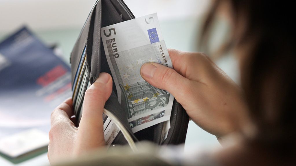 Eine Frau nimmt Geldscheine aus einem Portemonnaie
