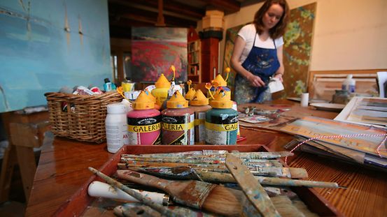 Malerin mit Pinseln und Farben in ihrem Atelier