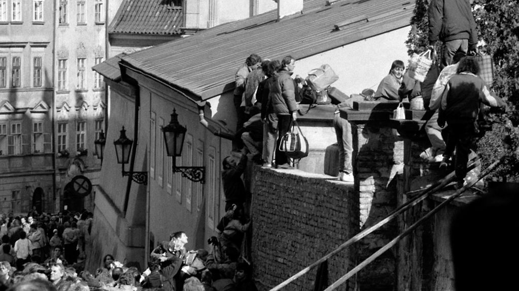 DDR-Flüchtlinge klettern am 4.10.1989 über Mauern, um auf das Botschaftsgelände in Prag zu gelangen.