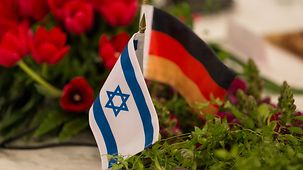 Ein israelisches und ein deutsches Fähnchen stehen auf einem Tisch.