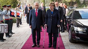 Bundeskanzlerin Angela Merkel geht neben Israels Präsidenten Shimon Peres.