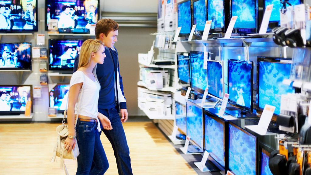 Ein junges Paar in der Fernsehabteilung eines Kaufhauses