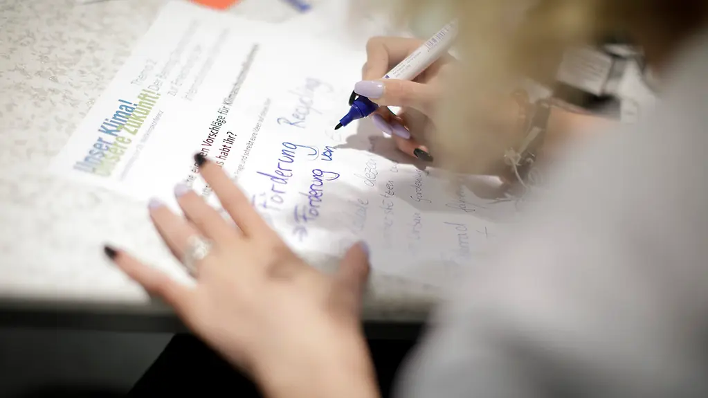 Hand mit Stift, die ein Plakat gestaltet