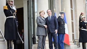 Federal Chancellor Angela Merkel is welcomed to the Élysée Palace by French President François Hollande.