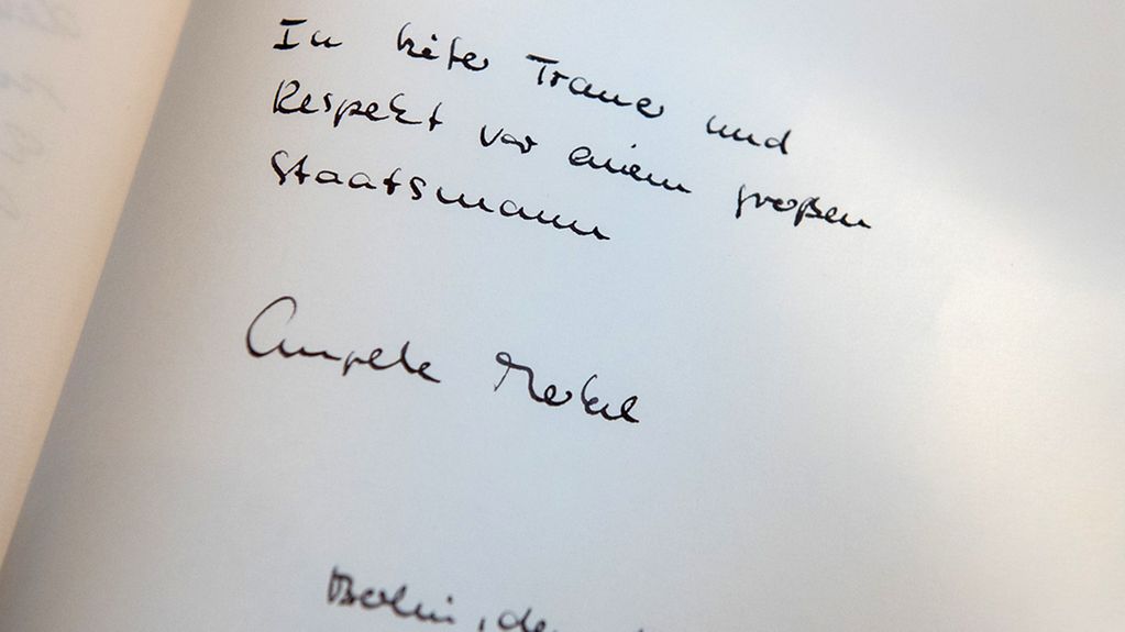 Chancellor Angela Merkel signs the book of condolence for the late Helmut Schmidt.