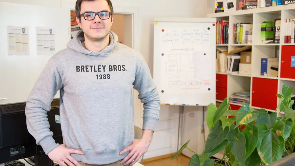 Lukas Niestroj steht vor einer Wand in seinem Ausbildungsbetrieb