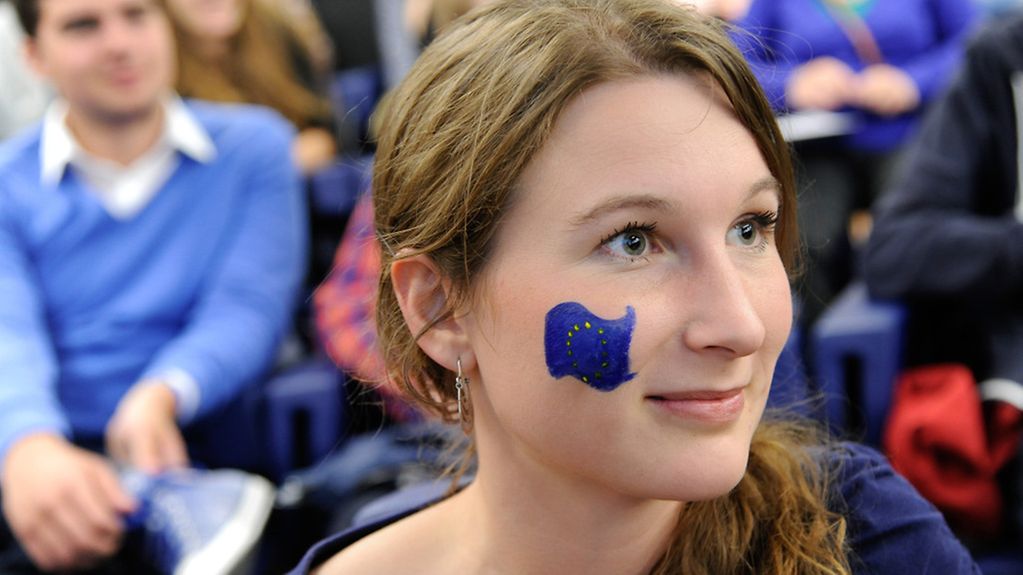 Junge Frau mit Europaflagge auf der Wange.