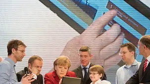 Merkel und Tusk an einem Tablet-PC.