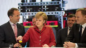 Merkel mit einem Lego-Bauteil.