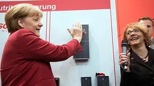 Merkel mit der Hand auf dem Scanner.