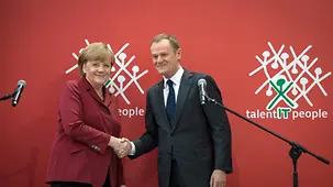 Merkel und Tusk schüttlen sich die Hände.