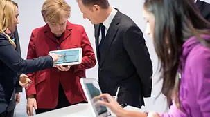 Merkel und Tusk an einem Tablet.