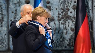Chancellor Angela Merkel is presented with the Presidential Award of Distinction by Israeli President Shimon Peres.
