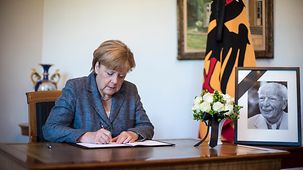 Bundeskanzlerin Angela Merkel trägt sich in das Kondolenzbuch für Walter Scheel ein.