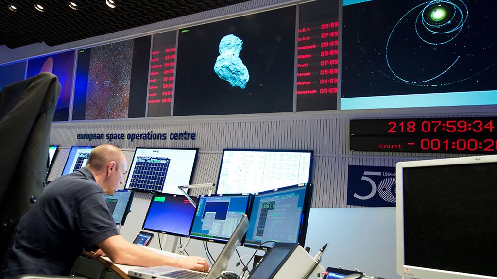 Eine Experte im Kontrollcenter der ESA beobachtet vor Bildschirmen die Mission Rosetta