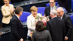 Chancellor Angela Merkel is presented with a bouquet following her re-election.