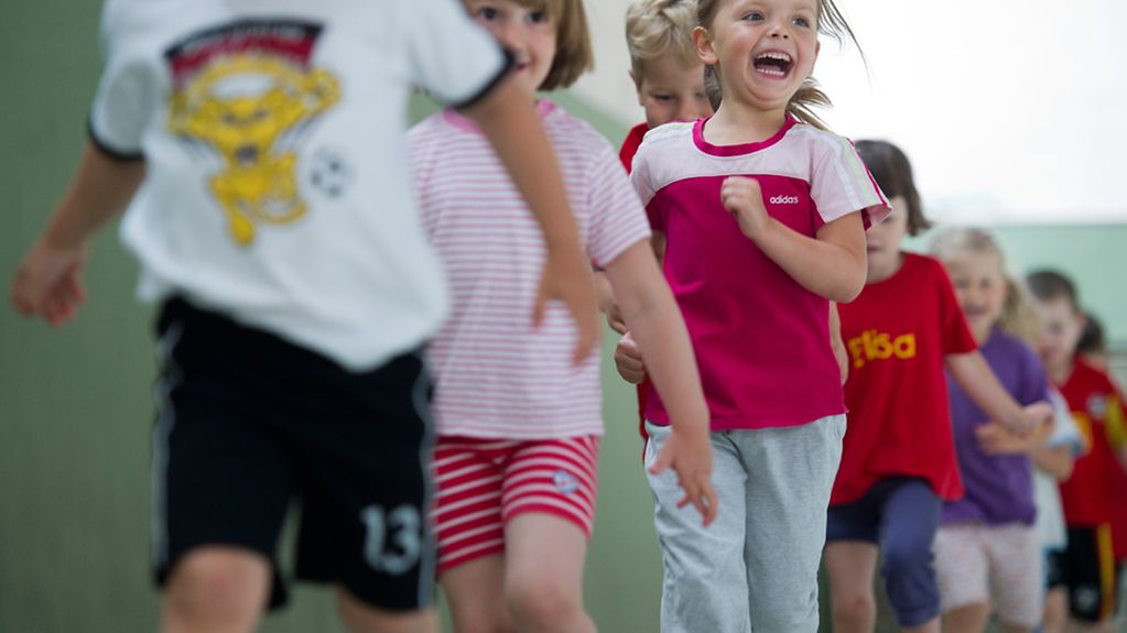 Kinder eines Kindergartens laufen in einer Sportstunde.