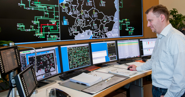 Ein Techniker kontrolliert über mehrere Monitore die landesweite Stromversorgung