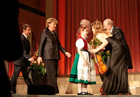Ein Schwarzwaldmädel übergibt der Violinistin Anne-Sophie Mutter einen Blumenstrauß nach deren Konzert vor den Staats- und Regierungschefs. Links Bundeskanzlerin Angela Merkel